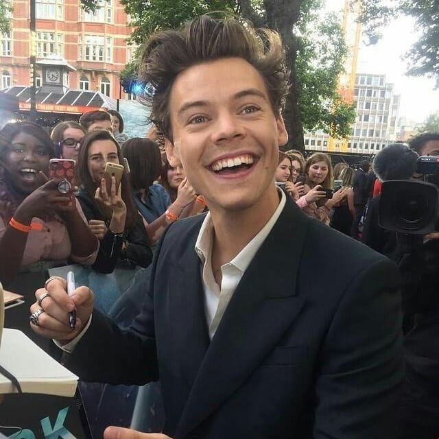 a man in a suit and white shirt is smiling at the camera while surrounded by people