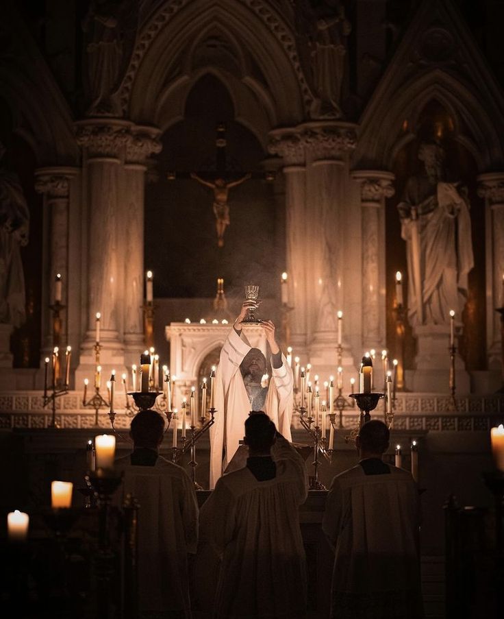 the priest is standing at the alter with candles in front of him and several other people