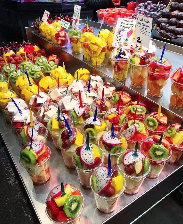 there are many different kinds of fruit in cups on the counter at this market stall