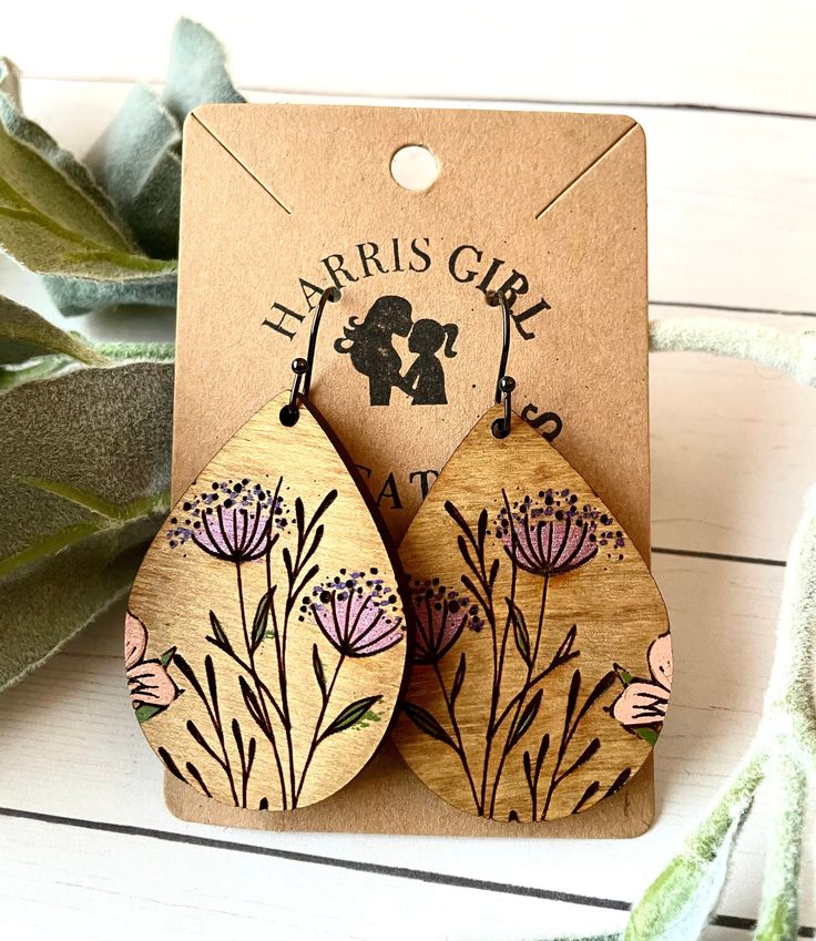 the wooden earrings are decorated with flowers and an image of a man kissing a woman