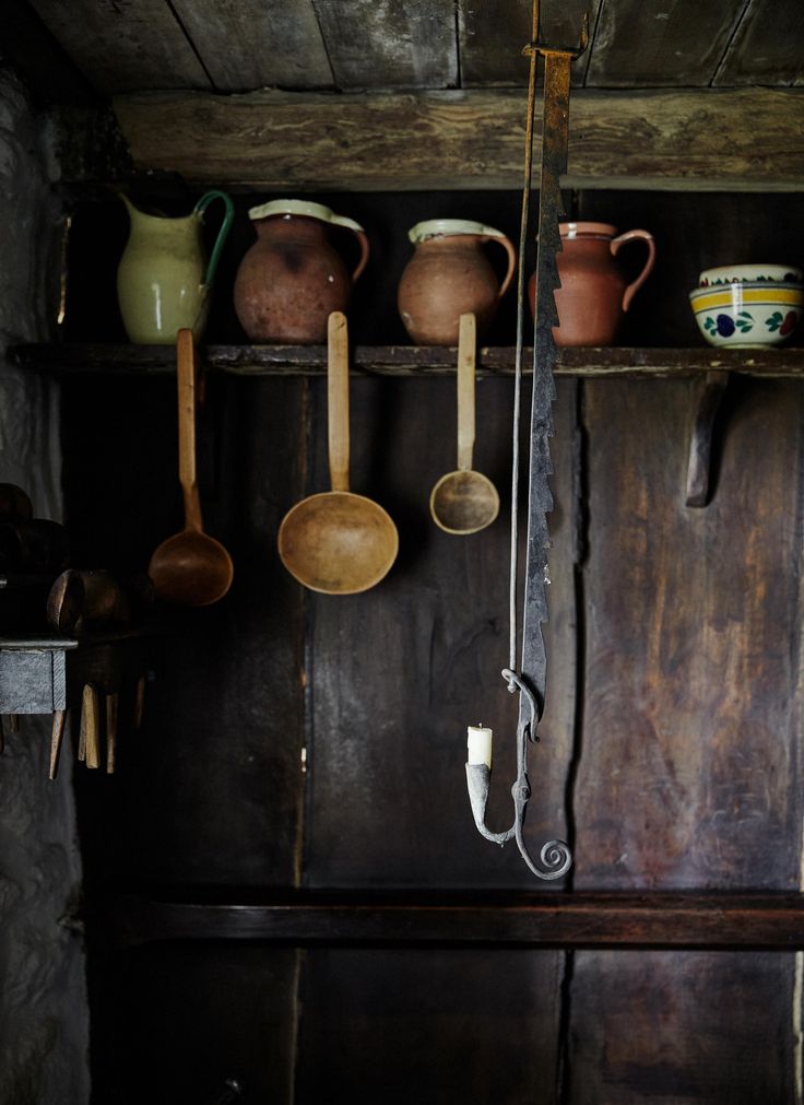 pots and pans are hanging on the wall in an old kitchen with wooden shelves