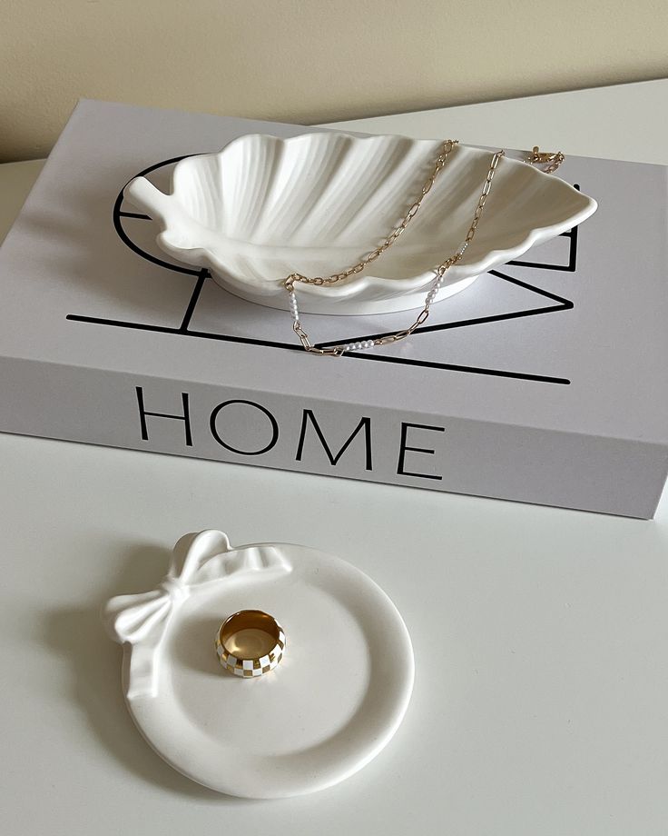 a white plate sitting on top of a table next to a box with a gold ring