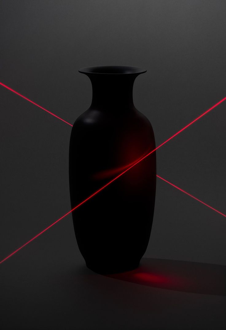 a black vase sitting on top of a table with red lasers in front of it