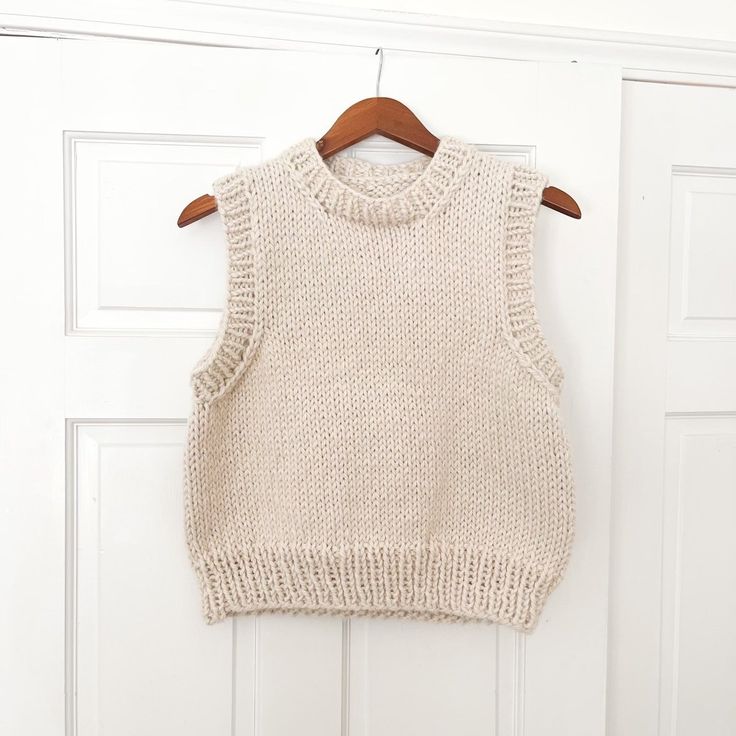 a knitted sweater hanging on a door with a wooden hanger in front of it