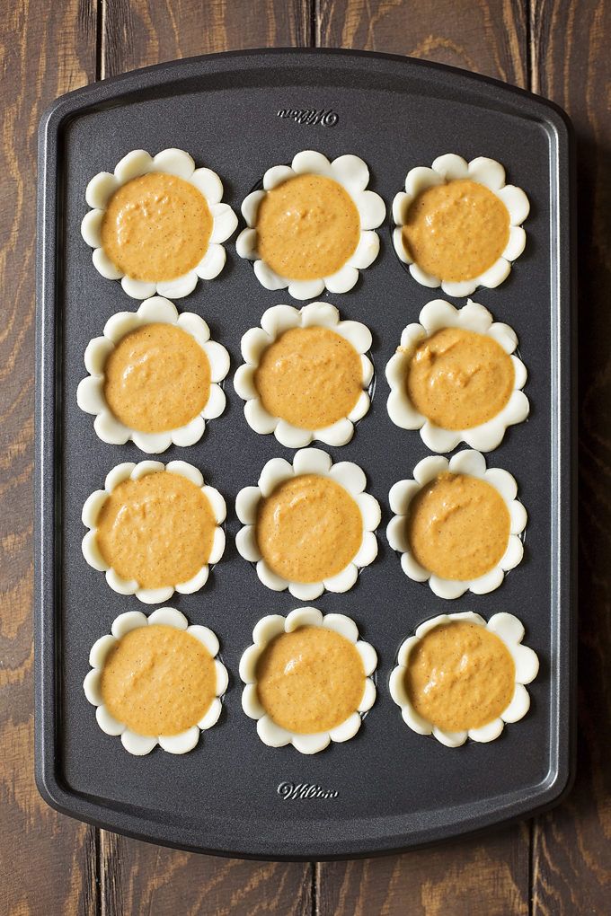 twelve cupcakes with peanut butter in the middle on a baking tray, ready to go into the oven