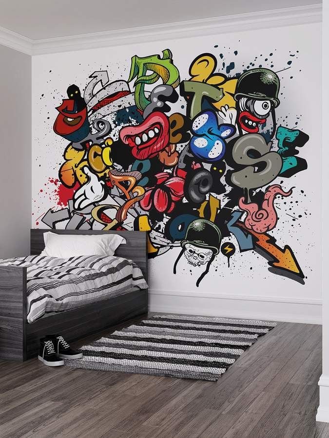 a room with a bed, rug and graffiti wallpaper on the walls in it