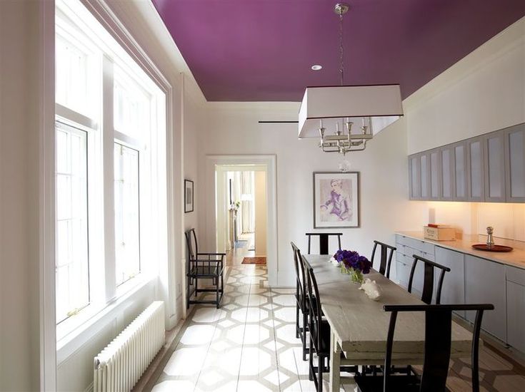 the dining room table is surrounded by black chairs and white tile flooring with purple painted ceiling