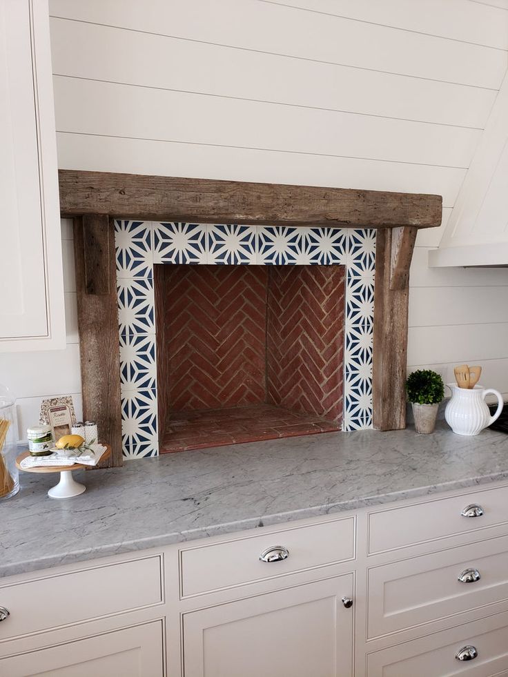 a fireplace in the middle of a kitchen with white cabinets