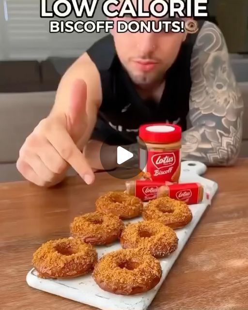 a man pointing at doughnuts on a tray with condiments in front of him