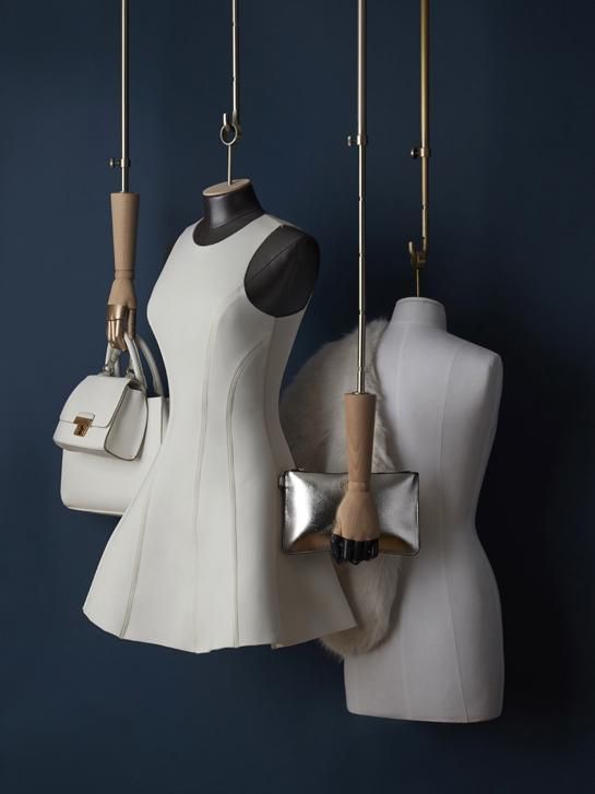 three mannequins are hanging on the wall and one is holding a purse