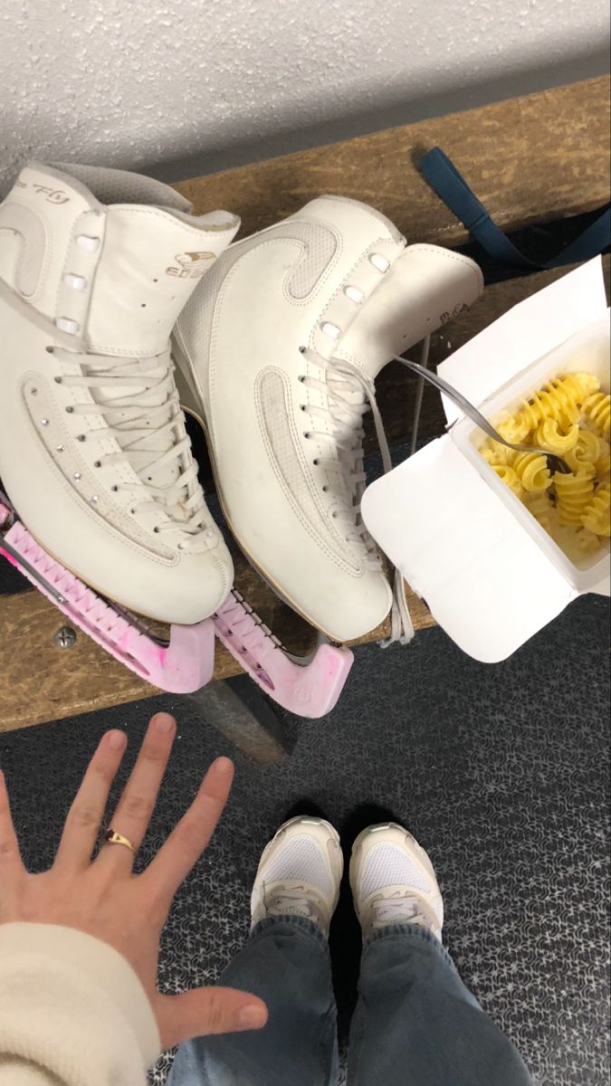 two pairs of white shoes sitting on top of a wooden table next to a bowl of noodles