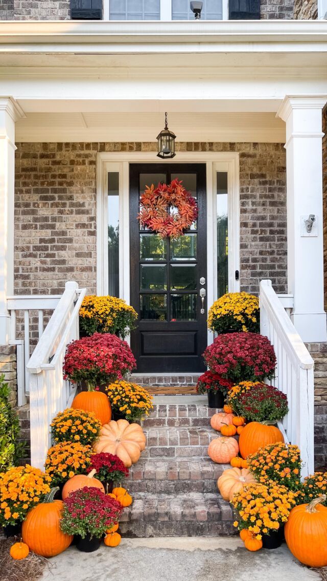 front porch decorated for fall with pumpkins and flowers