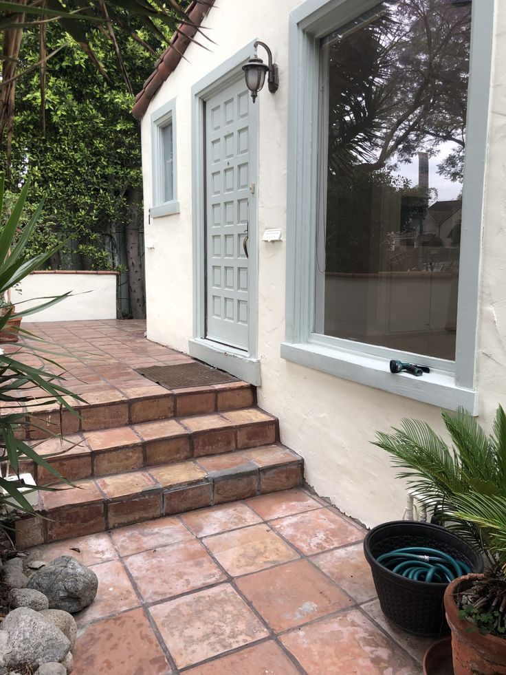 a house with steps leading to the front door and patio area, including potted plants