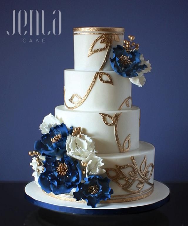 a three tiered wedding cake with blue and white flowers on the top, is displayed