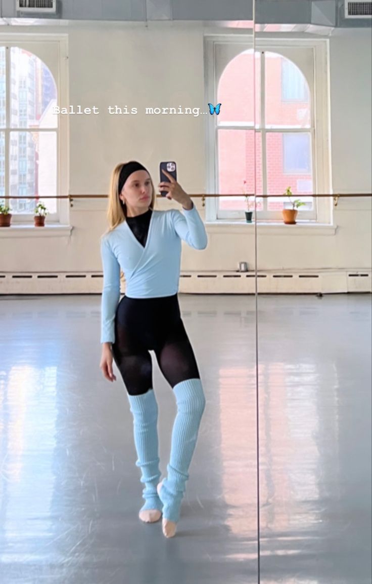 a woman is taking a selfie with her cell phone in an empty room while wearing tights and leggings