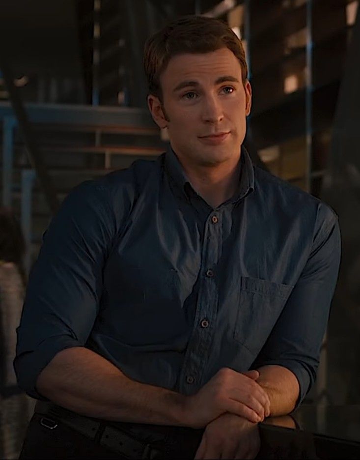 a man sitting at a table with his arms crossed in front of him, wearing a blue shirt