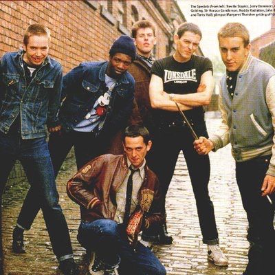 a group of young men standing next to each other on a brick road in front of a building