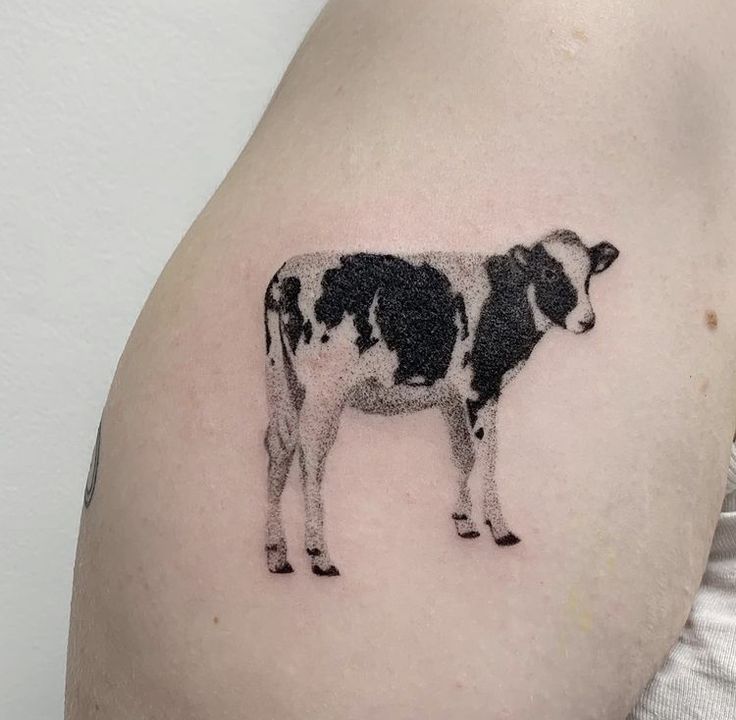 a black and white cow tattoo on the left side of the right arm