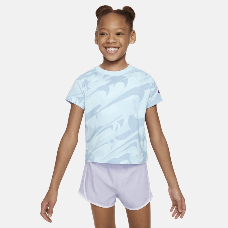 This colorful, Swooshtastic tee is sure to put some pep in your kiddo's step! It's made of cotton jersey, has a tagless crewneck for a comfy feel and the boxy cut creates a flattering, cropped look. Pair with the Nike Dri-FIT Prep in Your Step leggings for a coordinated style tailored for play. Blue Graphic Print Activewear With Short Sleeves, Summer Athleisure T-shirt For Playwear, Sportswear Tops For Playwear, Short Sleeve Sportswear Tops For Play, Cotton Athleisure T-shirt For Playwear, Nike Short Sleeve Activewear, Nike Sporty Tops For Playwear, Nike Blue Sportswear T-shirt, Sporty Nike Top For Playwear