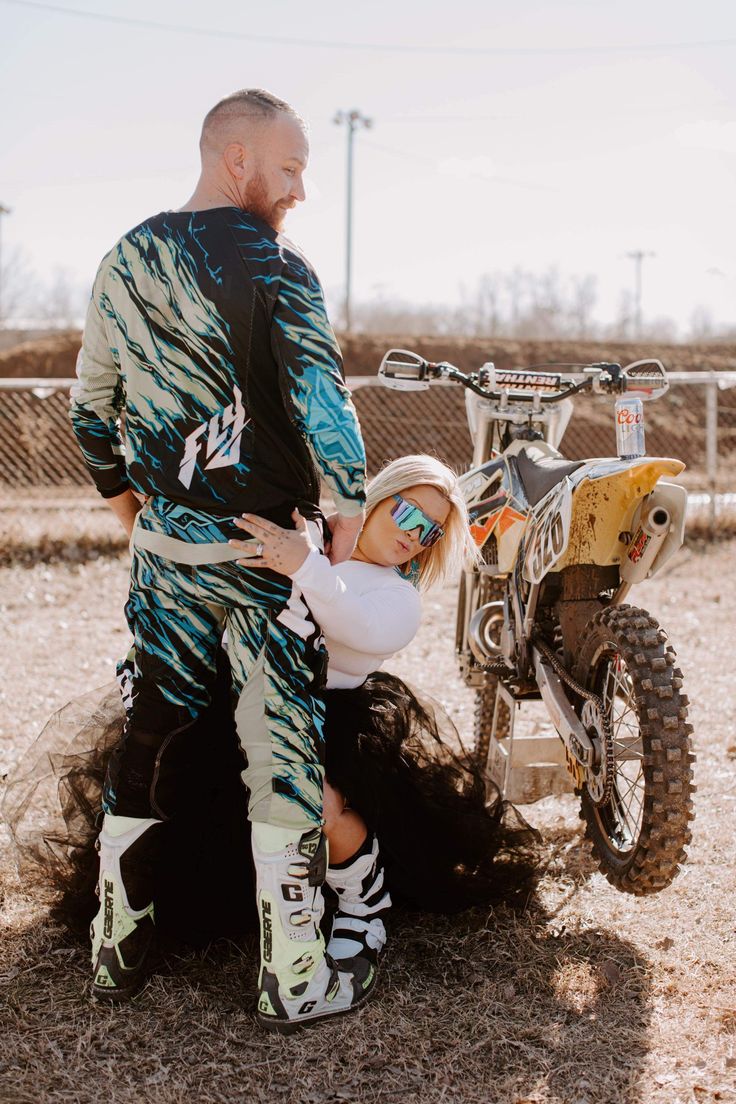 a man and woman standing next to a dirt bike