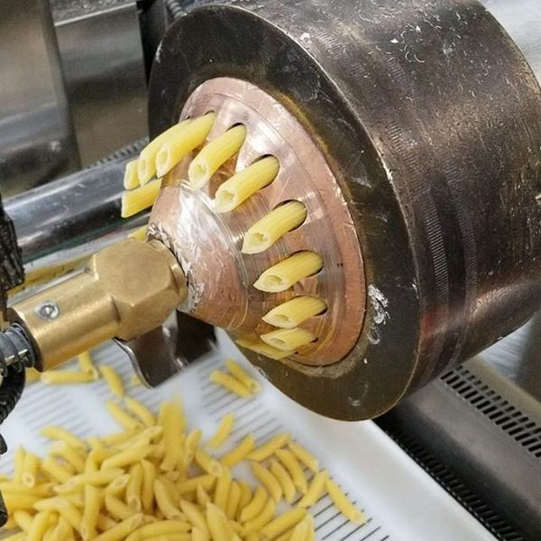 pasta being made in a machine with yellow noodles