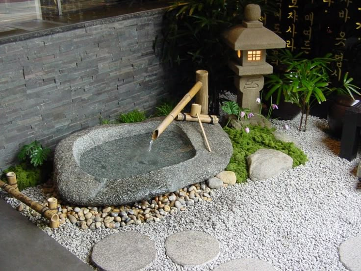 a small garden with rocks, gravel and plants in the corner next to a building