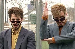 two men in suits and ties standing next to each other with their hands together,