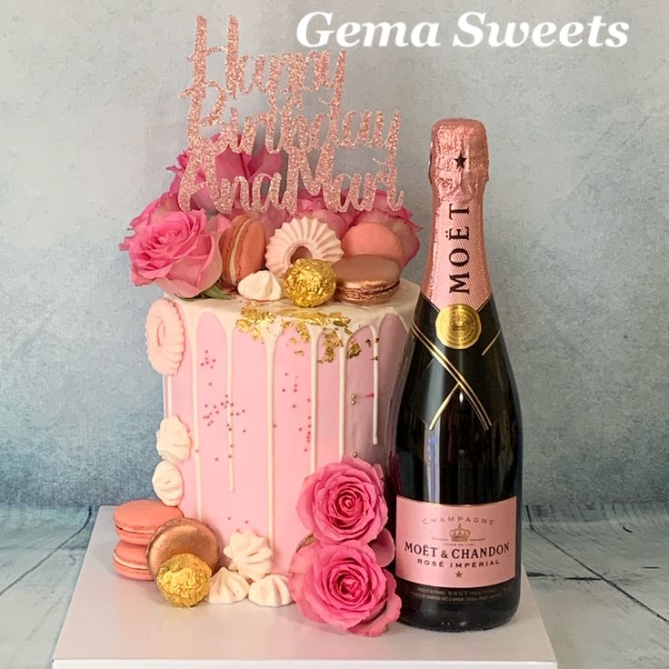 there is a cake with pink frosting and flowers next to a bottle of champagne