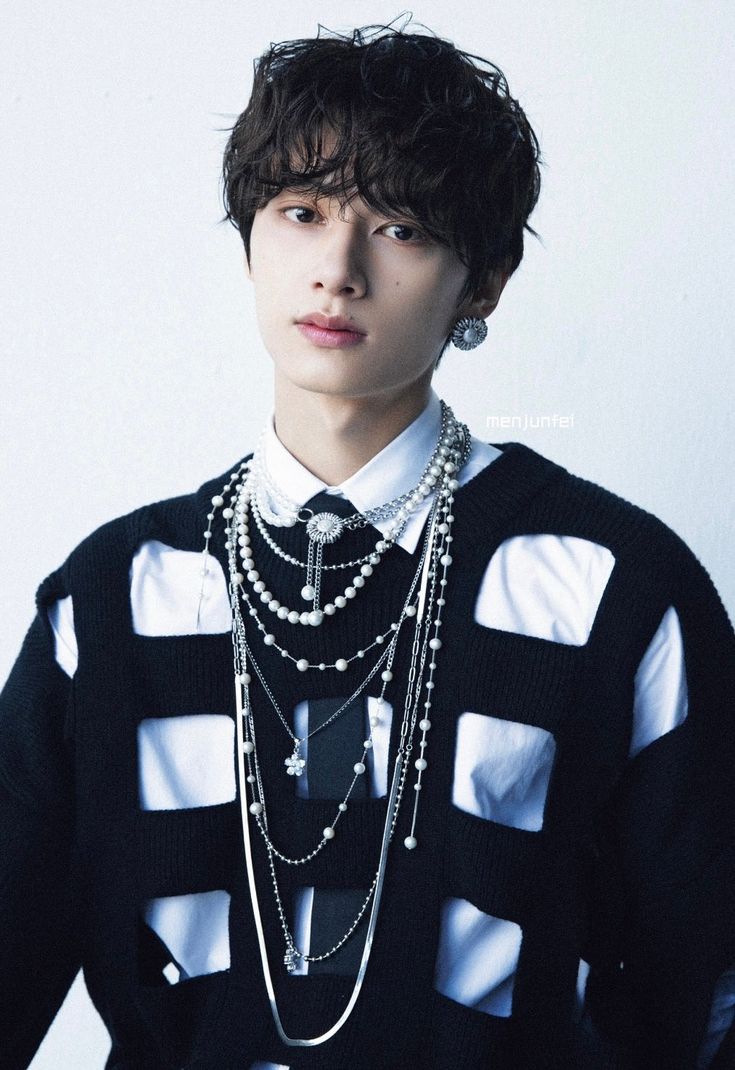 a young man in a black and white shirt with multiple necklaces on his neck