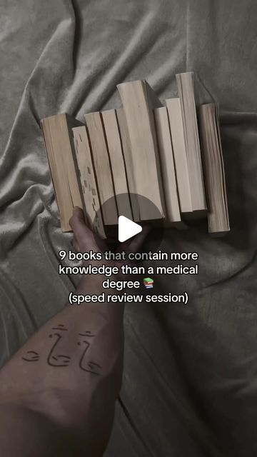 someone is holding some books in their hand and pointing them at the book on the bed