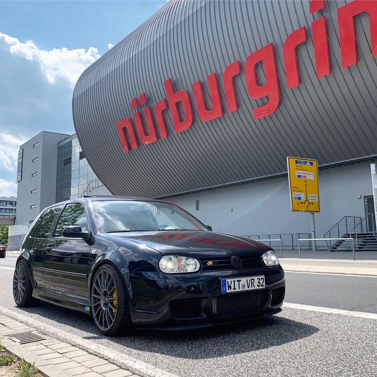 a black car parked in front of a large building with a huge sign on it's side