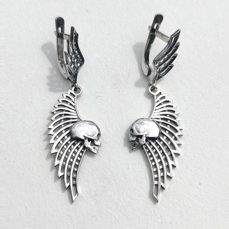 Skull and Wing Earrings Add a touch of edge to your style with these Skull and Wing Earrings. Crafted from solid sterling silver, these earrings feature an intricately detailed skull paired with an elegant wing design, weighing approximately 4.7 grams. They are perfect for those who appreciate unique, handcrafted jewelry with a gothic flair. ◆ Features: SKU: 41024 Brand new sterling silver 925 ring. Not plated!, 100% solid silver metal! Approx. weight of the product - 4.7g. Manufacturing and cou Winged Sterling Silver Earrings In Silver, Silver Winged Sterling Silver Earrings, Silver Sterling Silver Winged Earrings, Winged Sterling Silver Earrings As Gift, Winged Sterling Silver Earrings For Gift, Sterling Silver Winged Earrings Gift, Elegant Winged Metal Jewelry, Elegant Silver Winged Earrings, Gothic Sterling Silver Skull Earrings