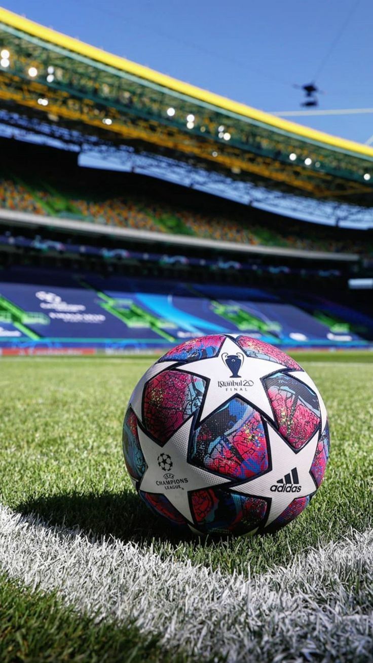 a soccer ball sitting on top of a field next to an empty stadium bleachers