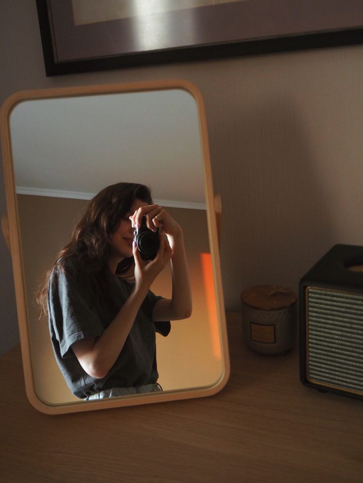 a woman taking a selfie in front of a mirror with her camera and an old radio