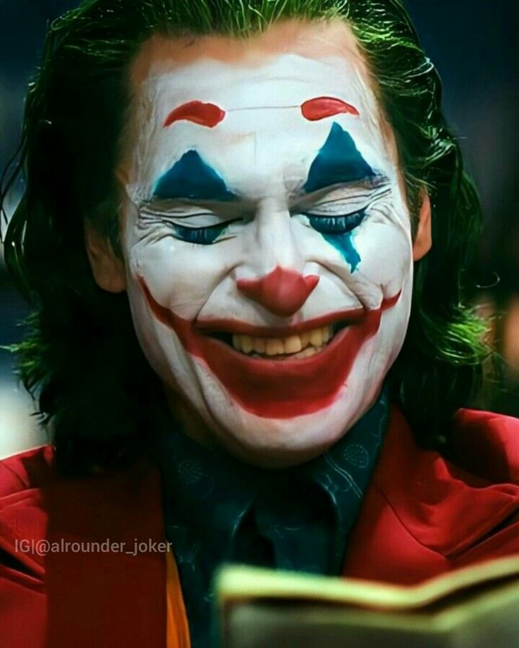 the joker is reading a book with his face painted red and blue, while he's smiling