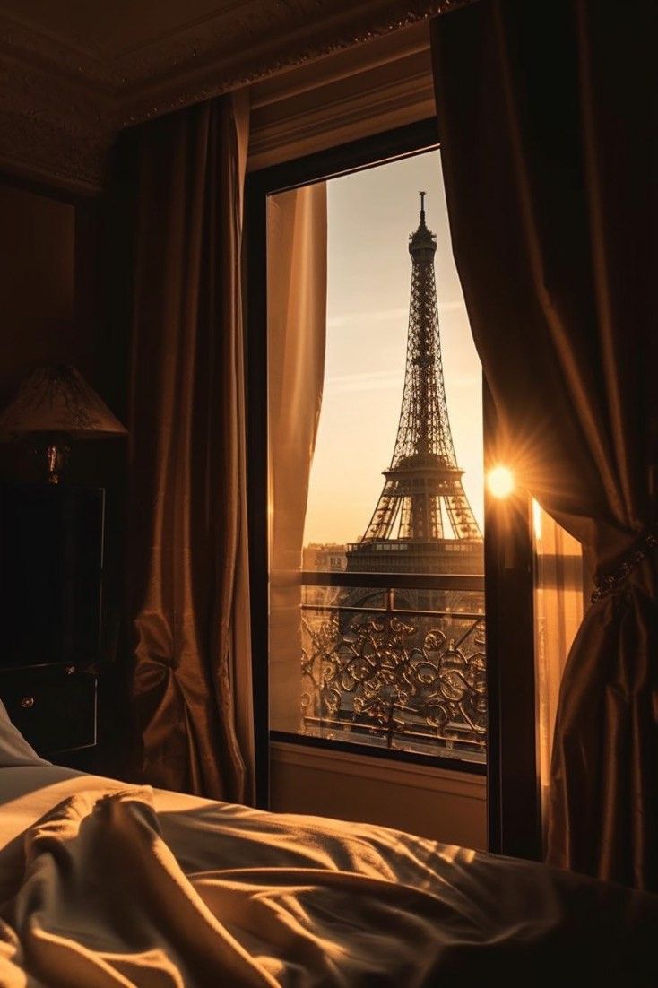 the eiffel tower is seen through an open window in this bedroom at sunset