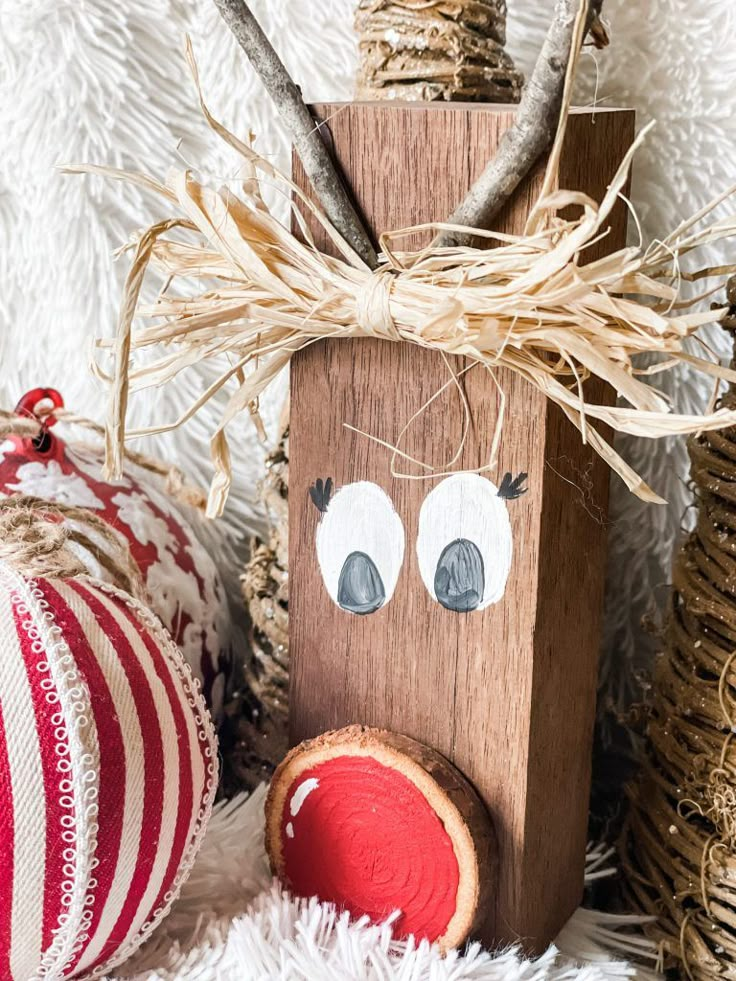 a wooden reindeer ornament sitting on top of a white blanket next to christmas decorations