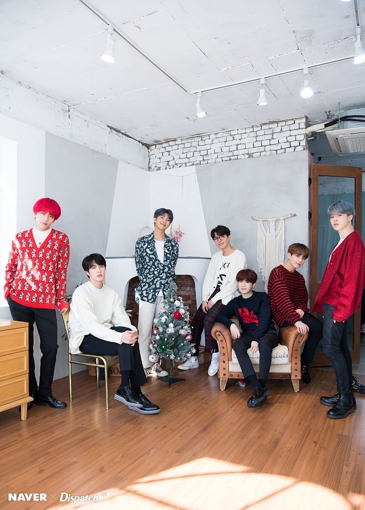 group of young men sitting on chairs in front of a christmas tree with red hair