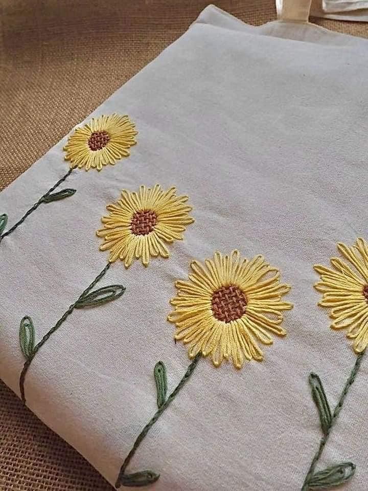 three sunflowers are embroidered onto a white cloth