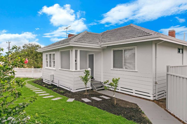 a white house sitting on top of a lush green field next to a fenced in yard