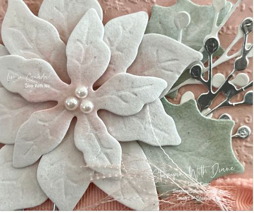 a close up of a flower on a piece of paper with leaves and pearls in the center