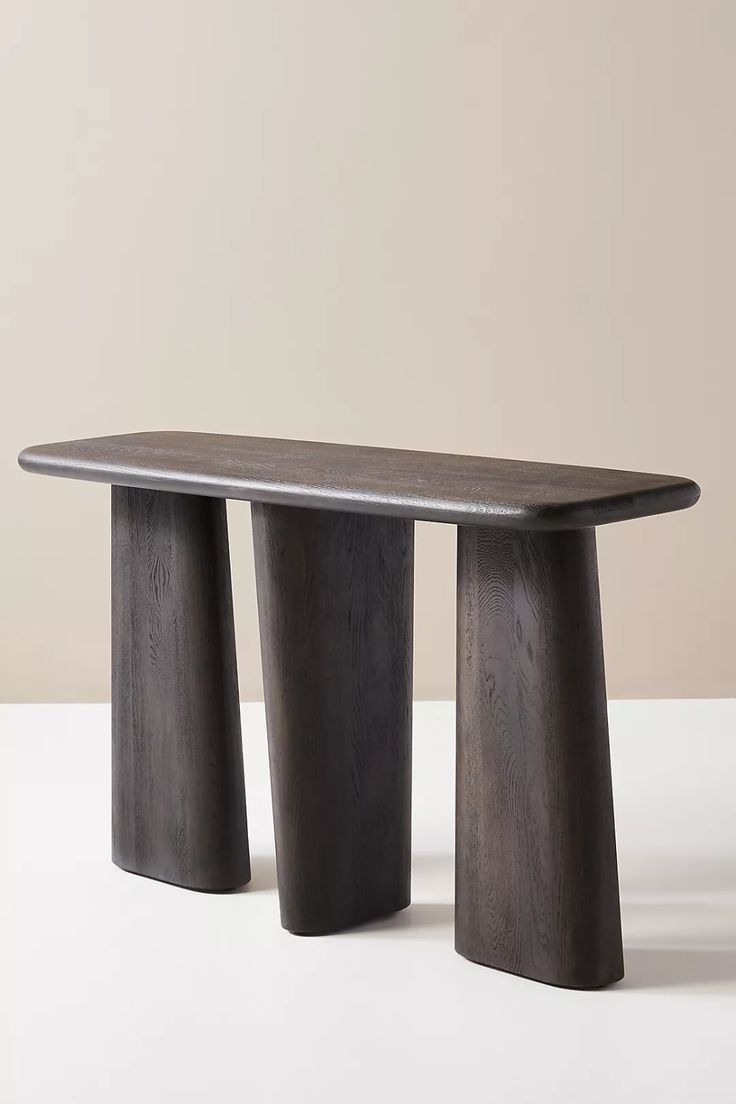 two wooden stools sitting next to each other on a white table with a beige wall in the background