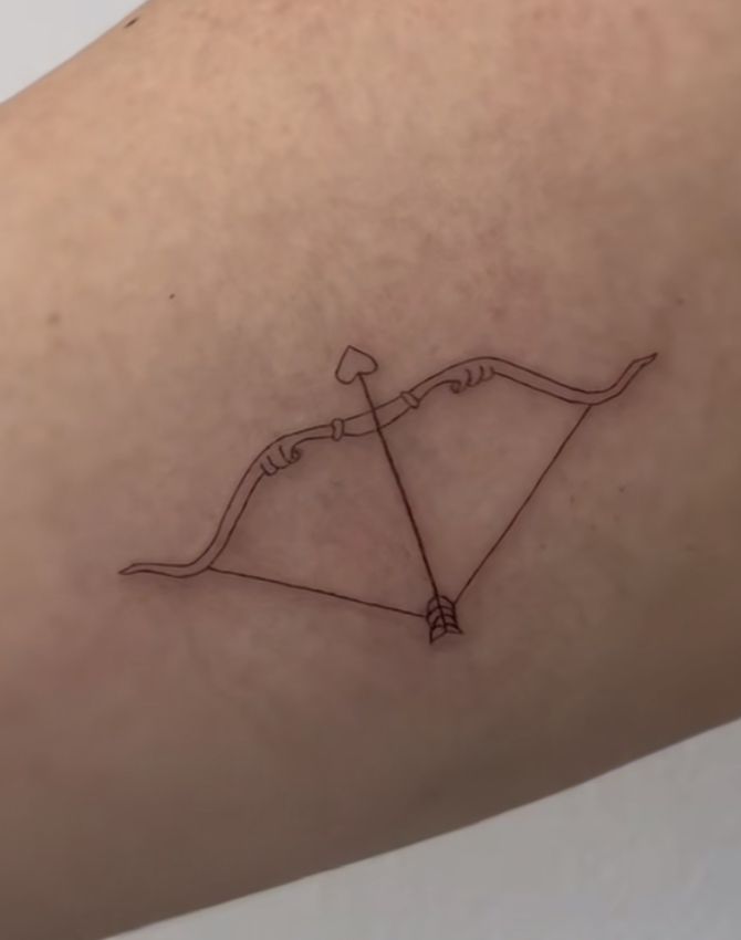 an arrow and bow tattoo on the back of a woman's arm, which is drawn in black ink