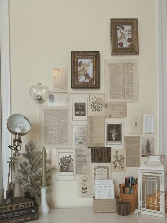 a white desk topped with lots of different types of books and pictures on the wall