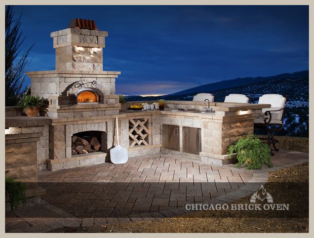 an outdoor kitchen with a pizza oven and grill in the middle of it at night