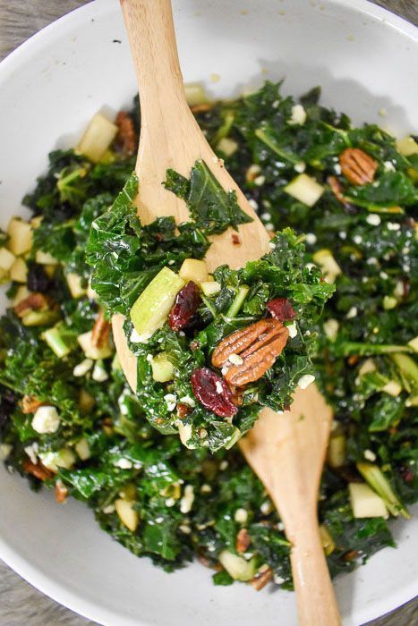 a white bowl filled with greens and nuts