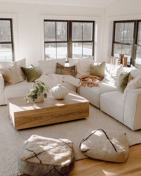 a living room filled with lots of furniture and pillows on top of a wooden floor