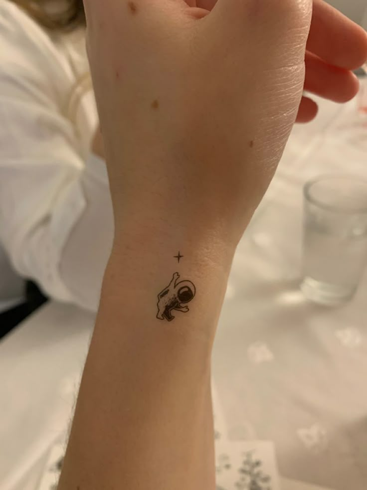 a person with a small tattoo on their wrist holding up her hand to the camera