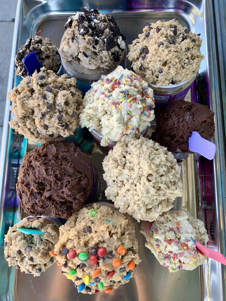 cupcakes and muffins on a tray with sprinkles in them