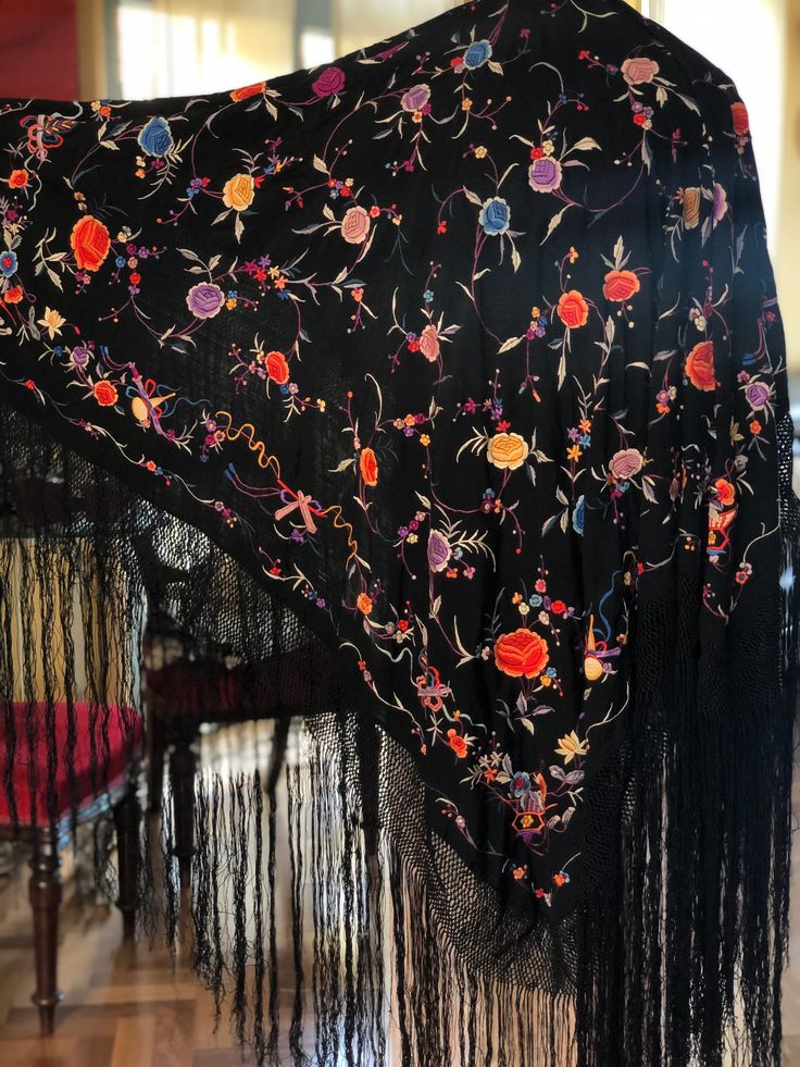 A magnificent Manton de Manila shawl made of black silk crepe fabric then heavily embroidered with colourful silk thread.  The embroidery is so well done you can barely tell which is the right side. The shawl is covered in embroidered flowers and leaves and around the edges are unusual depictions of musical symbols and bows. Quite a spectacular piece. In excellent condition  Measures 42" x 42" with a 20" woven fringe Silk Shawl With Intricate Embroidery, Multicolor Floral Embroidered Shawl With Traditional Drape, Embroidered Silk Shawl Scarf, Multicolor Shawl With Floral Embroidery, Silk Floral Print Shawl, Black Embroidered Silk Shawl, Traditional Black Silk Shawl, Embroidered Silk Shawl, Silk Shawl With Multicolor Embroidery